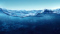 Deep blue ocean waves with underwater view showing crystal clear waters and dynamic surface movement against bright sky, suitable for environmental themes.