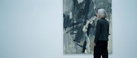 Senior woman with gray hair viewing large abstract painting in modern art gallery museum space for cultural education and artistic appreciation.