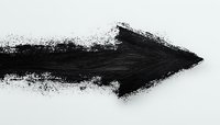 Black grunge arrow painted with rough brush strokes and scattered particles on white background, indicating direction or movement for graphic design projects.