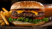Juicy cheeseburger with melted cheddar, crispy bacon, fresh lettuce, tomato slices on sesame bun served with golden french fries on wooden board. Food photography.
