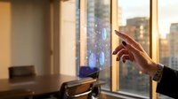 Businesswoman hand touching interactive holographic display with digital data visualization in modern office with city skyline view at sunset.