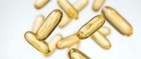 Golden supplement capsules scattered on white background for health and wellness marketing materials.