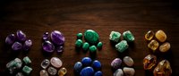 Collection of colorful healing crystals and gemstones arranged in groups on rustic wooden surface for meditation, chakra balancing, and spiritual wellness practices.