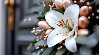 White lily bloom with rose gold Christmas ornaments and winter foliage creates elegant holiday arrangement, soft bokeh background adds dreamy atmosphere.