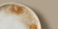Close-up of creamy coffee with cinnamon foam art on beige background. Morning beverage with warm spices for cafe menu and lifestyle content.