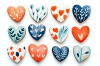 Handcrafted heart-shaped cookies with botanical and love-themed decorations in coral, navy blue, and teal icing on white background.