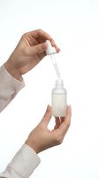 Hands holding dropper bottle with serum or oil, skincare routine application, cosmetic product use isolated on white background for beauty design.