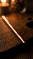 Elegant copper pen with ornate engravings resting on rustic wooden surface with warm ambient lighting creating cozy atmosphere for writing and creativity.