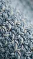 Close-up macro shot of gray knitted wool fabric texture with detailed stitching patterns and soft focus background for cozy winter fashion designs.