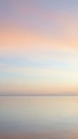 Serene dawn seascape with soft pastel gradient sky transitioning from purple to peach over calm ocean waters, ideal for wellness, travel, and lifestyle backgrounds.