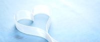 White ribbon forming heart shape on soft blue textured background for romantic occasions, weddings, valentines day celebrations and love concepts.