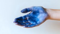 Open palm of Caucasian person with blue paint or dye staining the skin, displayed against white background for creative arts and crafts projects.