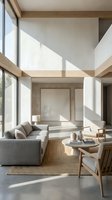 Minimalist living room with double-height ceiling, natural light streaming through large windows, gray upholstered sofa, wooden furniture, and neutral tones for contemporary interior design.