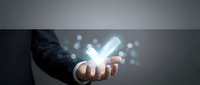 Business professional holding glowing checkmark symbol with digital particles representing success, approval and achievement in corporate environment.