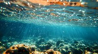 Underwater view of sunlight rays penetrating ocean surface creating magical light beams through turquoise water with ripples and bubbles. Tranquil seascape scene.
