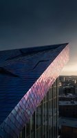 Modern skyscraper with geometric blue and pink facade at sunset, showcasing contemporary architecture and urban design for commercial, real estate, and corporate projects.