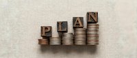 Wooden letter blocks spelling PLAN arranged on ascending stacks of coins representing financial planning, budgeting strategy and investment growth concept.