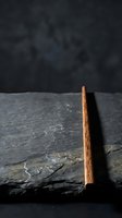 Wooden chopstick on dark slate stone surface with textured background for Asian cuisine and restaurant presentation.