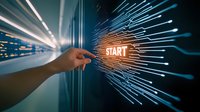 Hand pressing glowing START button with dynamic light rays in modern server room representing business launch and digital transformation concepts.