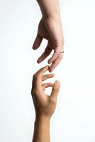 Two hands reaching toward each other in gentle touching gesture on white background symbolizing connection, support, help, teamwork and human relationships.