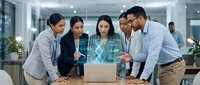 Diverse business team collaborating around laptop with holographic data visualization in modern office environment for corporate technology solutions.