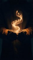 Hands cupping glowing golden energy spiral with magical particles floating upward against dark background for spiritual and mystical design concepts.