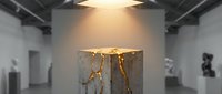 Concrete pedestal with glowing golden cracks displayed in a modern art gallery under dramatic spotlight, kintsugi-inspired sculpture concept.