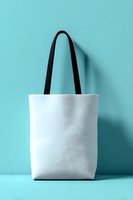 White canvas tote bag with black handles against turquoise background, isolated for mockup use in retail, branding, and eco-friendly shopping promotions.