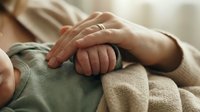 Tender moment as a newborn baby grasps a mothers hand, soft natural light highlighting the gentle bond of love and new parenthood.