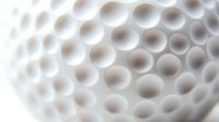 Close-up macro view of white golf ball dimples showing detailed hexagonal pattern texture and surface structure for sports equipment design.