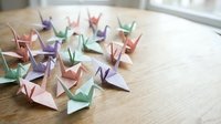 Colorful origami paper cranes arranged on wooden table surface creating peaceful zen meditation atmosphere for mindfulness and relaxation concepts.