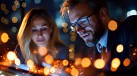 Caucasian couple enjoying romantic evening with magical bokeh lights and warm atmosphere. Man wearing glasses smiles at blonde woman against blurred city background.