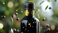 Dark glass bottle with olive oil against blurred green background with flying coffee beans and leaves, golden bokeh lights creating premium product atmosphere.