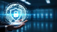 Digital cybersecurity concept with glowing shield and padlock hologram floating above businessman hand in modern data center environment.
