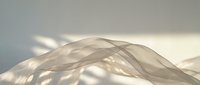 Flowing translucent fabric waves creating elegant abstract forms with soft lighting and shadows for luxury design projects.