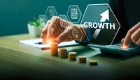 Business growth concept with digital icons and coin stacks on desk. Professional workspace showing financial progress and investment strategy planning.