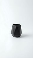 Black geometric ceramic vessel with angular faceted design isolated on white background, suitable for home decor, product photography, and interior design projects.