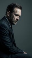 Mature businessman in dark suit with contemplative expression, professional portrait with dramatic lighting for corporate and business concepts.
