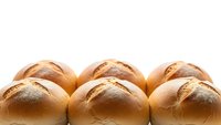 Fresh baked bread rolls arranged in rows with golden brown crusts and flour dusting on white background for bakery and food design projects.