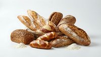 Assorted artisan breads including baguettes and rolls with seeds and flour dusting on white background for bakery and food styling.