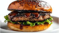 Juicy grilled beef burger with fresh lettuce and dark sauce on brioche bun, close up view on white plate, selective focus on meat patty and glaze.