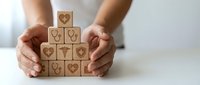 Hands protecting wooden blocks with healthcare medical icons symbols for health insurance wellness protection concept.