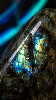 Labradorite gemstone displaying vibrant blue and green iridescent flashes against dark background with colorful light streaks for jewelry and mineral collection.