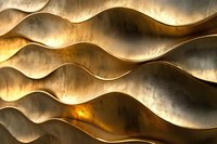 Abstract wavy golden metallic surface with dramatic light and shadow creating dynamic ripple pattern. Luxury background design for elegant presentations.