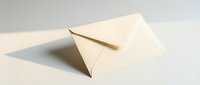Cream paper envelope standing upright on a light surface, casting a soft shadow, evoking elegance and simplicity in correspondence.