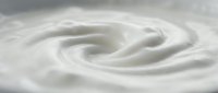 Creamy white swirl texture with smooth flowing curves creating elegant spiral pattern for food packaging and dairy product advertising backgrounds.