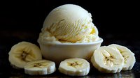 Fresh vanilla ice cream scoop in white bowl with sliced ripe banana pieces arranged on dark background, close up view of creamy frozen dessert.