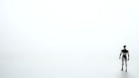 Lone figure standing in vast empty white space representing isolation, minimalism, and solitude for conceptual design projects.