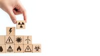 Hand placing wooden cube with nuclear symbol completing energy source pyramid on white background for environmental presentations.