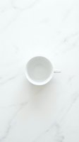 Empty white ceramic mug on marble surface, overhead view. Minimalist tabletop styling for beverage, coffee, tea, and kitchen design projects.